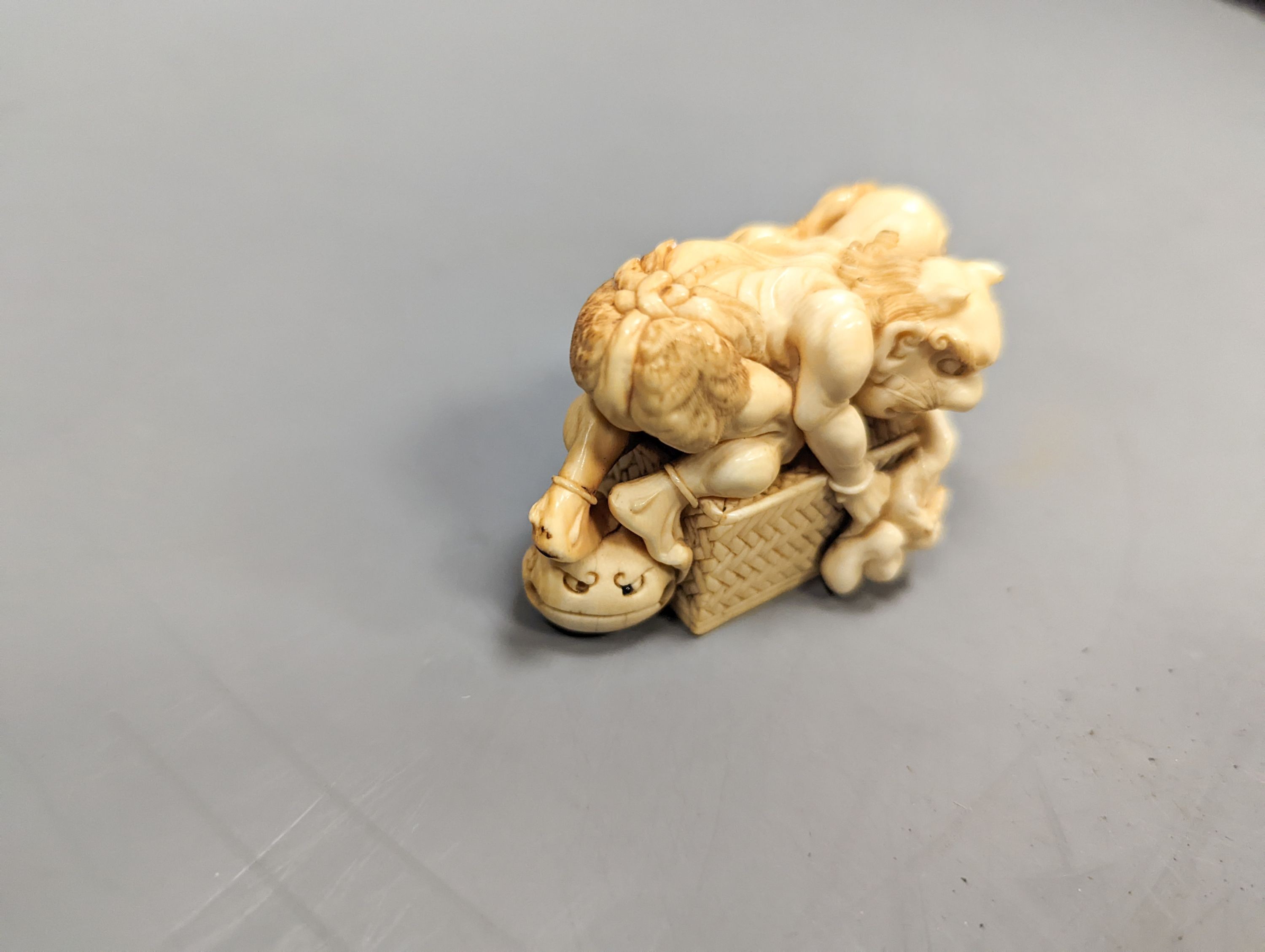 A Japanese ivory okimono of on a box, Meiji period, signed, 6 cms wide.